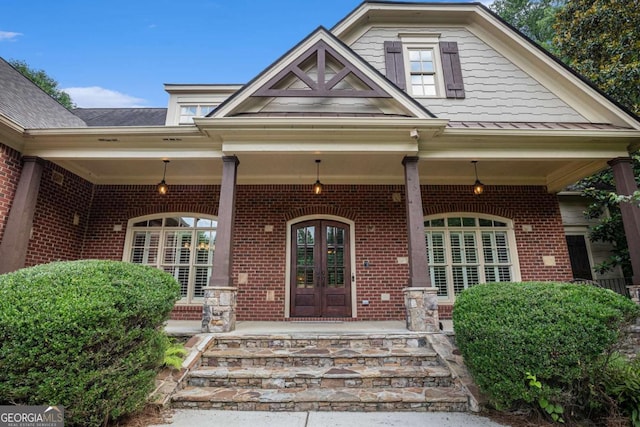 287 Scenic Falls Blvd, Hoschton, GA 30548 - property entrance featuring a porch, brick siding, french doors, and a standing seam roof
