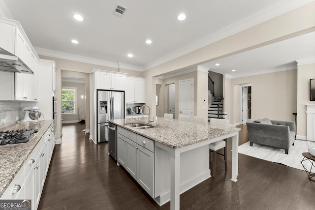 4130 Millbrook Ct, Suwanee, GA 30024 - kitchen featuring appliances with stainless steel finishes, open floor plan, dark wood-style flooring, a breakfast bar, and a center island with sink