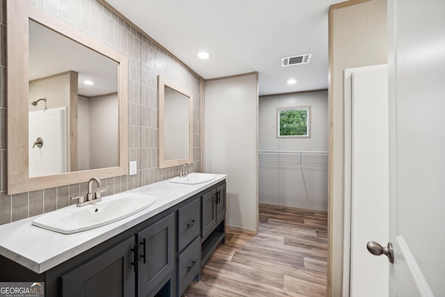 1413 Hephzibah Mcbean Rd, Hephzibah, GA 30815 - bathroom with double vanity, wood finished floors, tile walls, decorative backsplash, and a walk in closet