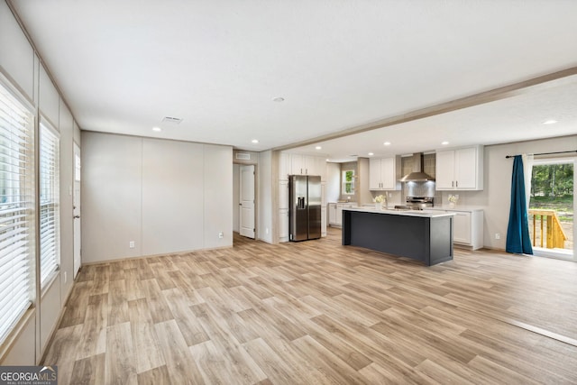1413 Hephzibah Mcbean Rd, Hephzibah, GA 30815 - kitchen with appliances with stainless steel finishes, wall chimney range hood, light countertops, white cabinets, and light wood finished floors