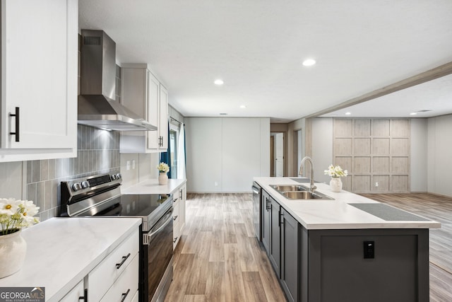 1413 Hephzibah Mcbean Rd, Hephzibah, GA 30815 - kitchen with stainless steel appliances, wall chimney exhaust hood, light wood-style floors, white cabinetry, and backsplash