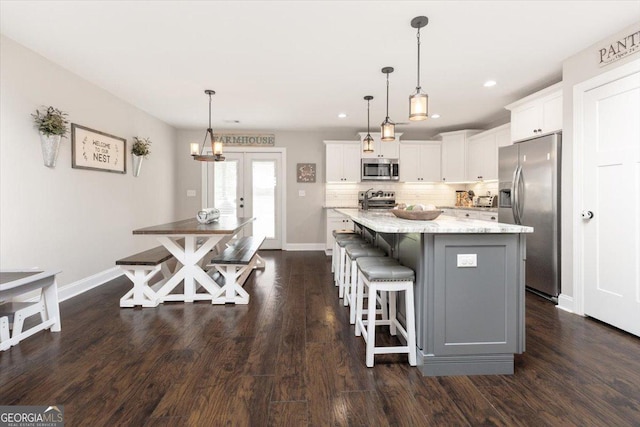 311 Kendall Ct, Perry, GA 31069 - kitchen with stainless steel appliances, white cabinetry, a breakfast bar, a center island, and light stone countertops