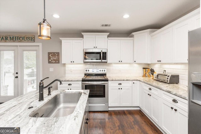 311 Kendall Ct, Perry, GA 31069 - kitchen with appliances with stainless steel finishes, white cabinetry, pendant lighting, decorative backsplash, and dark wood-style floors
