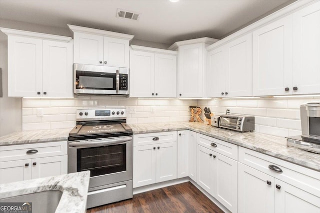 311 Kendall Ct, Perry, GA 31069 - kitchen with stainless steel appliances, white cabinets, dark wood finished floors, and tasteful backsplash