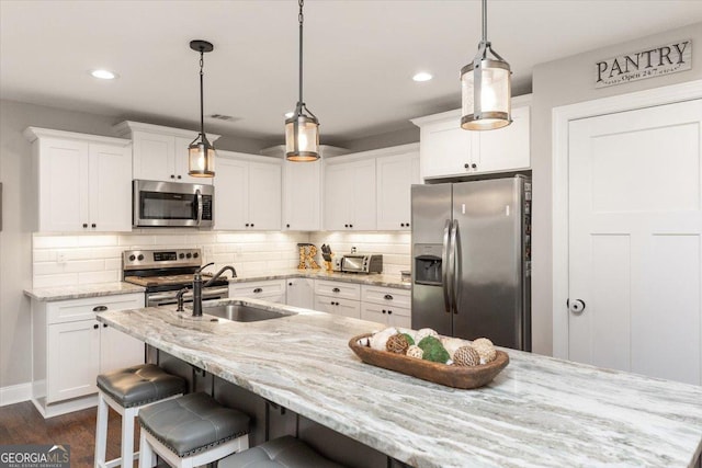 311 Kendall Ct, Perry, GA 31069 - kitchen with stainless steel appliances, white cabinetry, a kitchen breakfast bar, decorative backsplash, and dark wood-type flooring