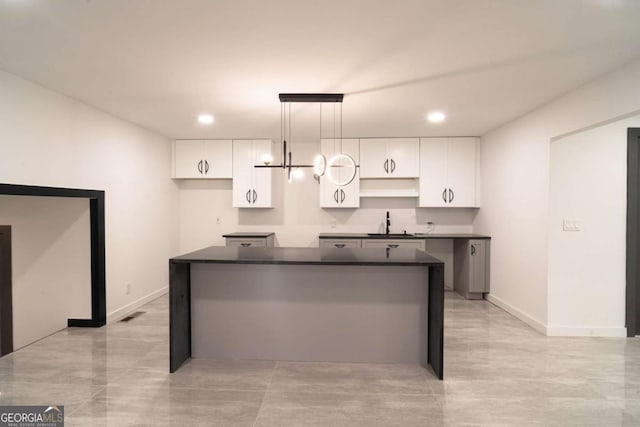 69 N Hearn Rd, Ellenwood, GA 30294 - kitchen with a kitchen island, dark countertops, white cabinetry, recessed lighting, and hanging light fixtures