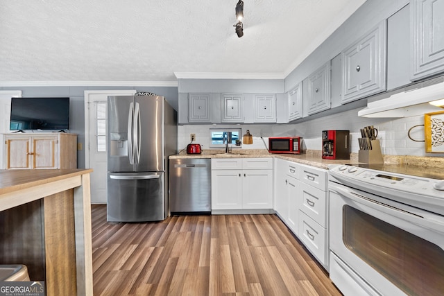 321 Barbara Point Rd, Sparta, GA 31087 - kitchen with appliances with stainless steel finishes, ornamental molding, a textured ceiling, light wood-style floors, and tasteful backsplash