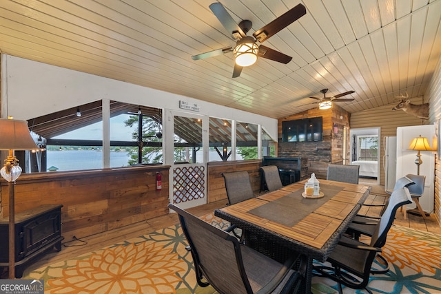 321 Barbara Point Rd, Sparta, GA 31087 - dining room with wood finished floors, vaulted ceiling, ceiling fan, a wood stove, and wooden walls