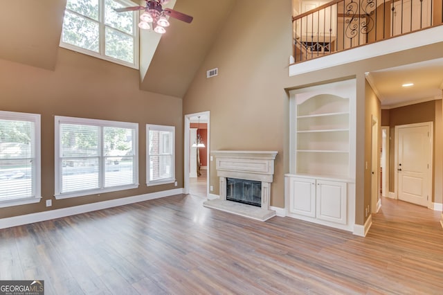 3217 Aberrone Pl, Buford, GA 30519 - unfurnished living room featuring a high ceiling, a glass covered fireplace, ceiling fan, plenty of natural light, and light wood-style flooring