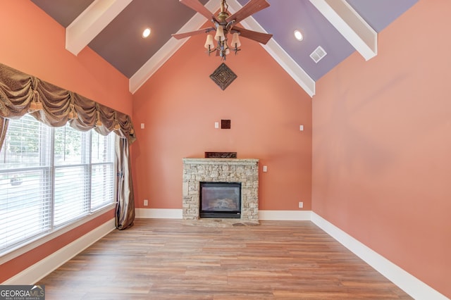 3217 Aberrone Pl, Buford, GA 30519 - unfurnished living room featuring beamed ceiling, high vaulted ceiling, ceiling fan, a stone fireplace, and light wood-style floors