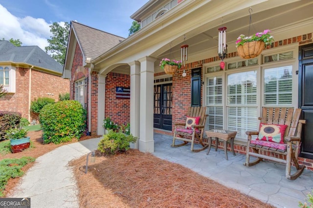 3217 Aberrone Pl, Buford, GA 30519 - doorway to property featuring brick siding, covered porch, and roof with shingles