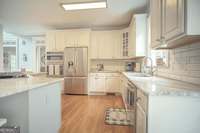 361 Fairway Cir, Monroe, GA 30656 - kitchen featuring appliances with stainless steel finishes, light wood finished floors, light stone counters, tasteful backsplash, and glass insert cabinets