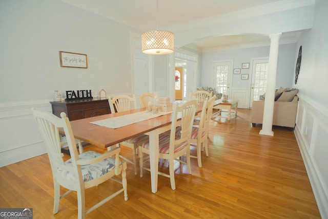 361 Fairway Cir, Monroe, GA 30656 - dining area featuring a decorative wall, crown molding, arched walkways, ornate columns, and light wood finished floors
