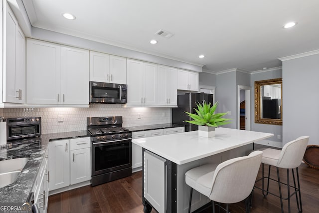 1967 Cogar Dr, Decatur, GA 30032 - kitchen featuring stainless steel appliances, crown molding, decorative backsplash, a kitchen bar, and white cabinets