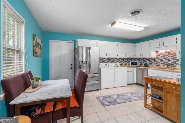 1777 Cedar Shoals Dr Unit 1775, Athens, GA 30605 - kitchen featuring appliances with stainless steel finishes, washing machine and clothes dryer, backsplash, light countertops, and a textured ceiling