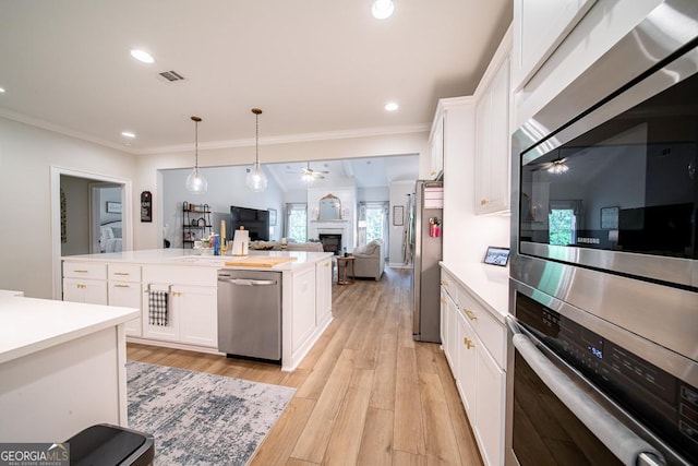 96 Cypress Trl, Fortson, GA 31808 - kitchen featuring appliances with stainless steel finishes, a ceiling fan, a fireplace, light countertops, and light wood-style flooring
