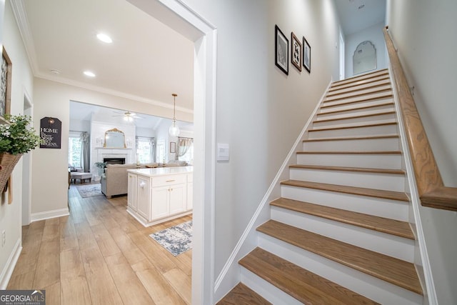 96 Cypress Trl, Fortson, GA 31808 - staircase with a fireplace, a ceiling fan, crown molding, wood finished floors, and recessed lighting