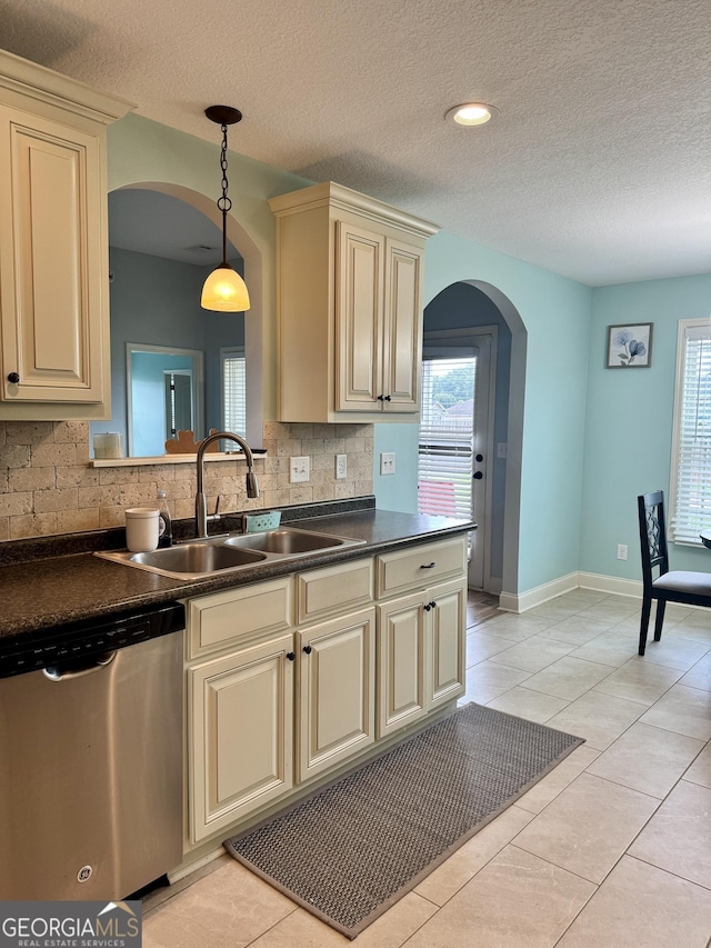 139 Raymond Cir, Warner Robins, GA 31088 - kitchen with cream cabinetry, stainless steel dishwasher, arched walkways, dark countertops, and backsplash