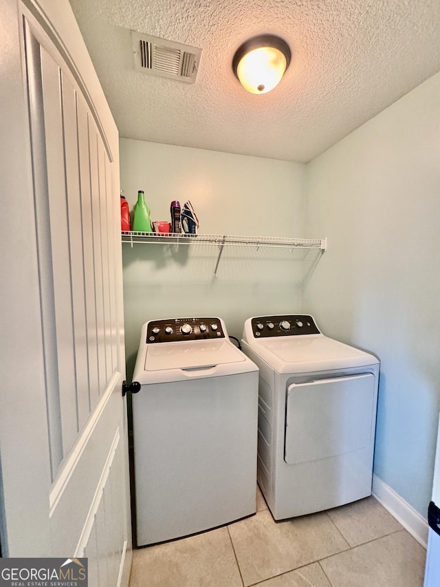 139 Raymond Cir, Warner Robins, GA 31088 - laundry area featuring washing machine and dryer, a textured ceiling, and light tile patterned floors