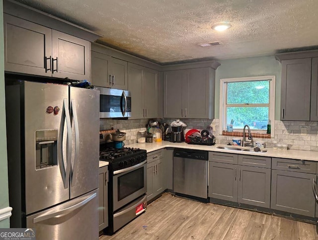 2433 Robin Ridge Dr, Dacula, GA 30019 - kitchen with stainless steel appliances, gray cabinets, light countertops, light wood-type flooring, and a textured ceiling