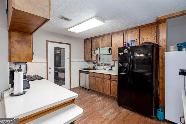 3470 Hill Ln, Acworth, GA 30102 - kitchen with black refrigerator with ice dispenser, stainless steel dishwasher, freestanding refrigerator, light countertops, and light wood-style floors
