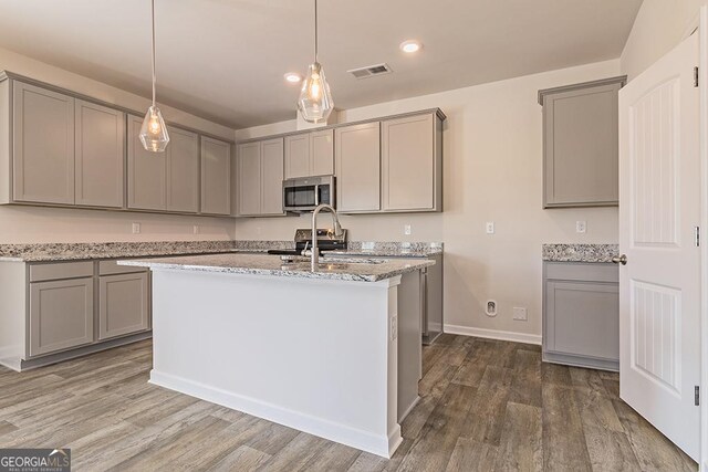 225 Rusty Plow Ln Unit 72, Perry, GA 31069 - kitchen with stainless steel microwave, gray cabinetry, light stone countertops, dark wood-style floors, and decorative light fixtures