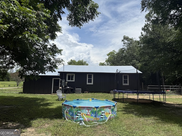 3052 Effingham Hwy, Sylvania, GA 30467 - rear view of house with a trampoline, board and batten siding, a lawn, and an outdoor pool