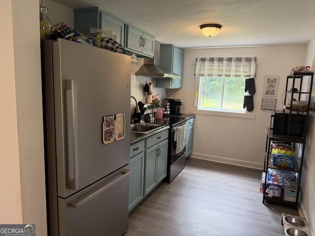 3052 Effingham Hwy, Sylvania, GA 30467 - kitchen with freestanding refrigerator, light wood finished floors, wall chimney range hood, electric range, and dark countertops
