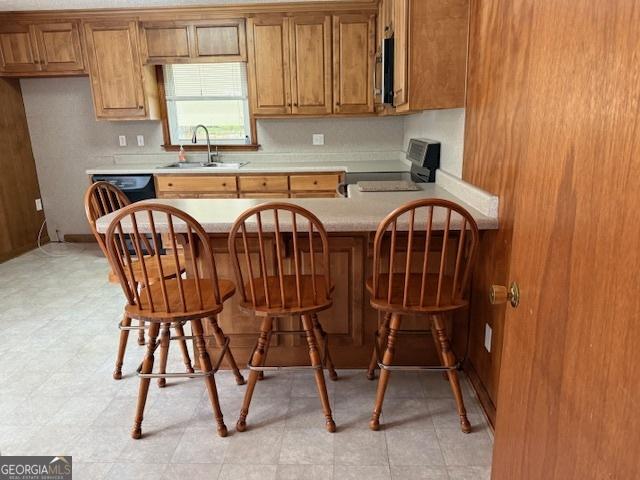 163 NW R St, Thomaston, GA 30286 - kitchen with range, brown cabinets, stainless steel microwave, and light countertops