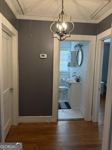 502 S Hull St, Sylvania, GA 30467 - hallway featuring attic access, wood finished floors, a chandelier, and crown molding