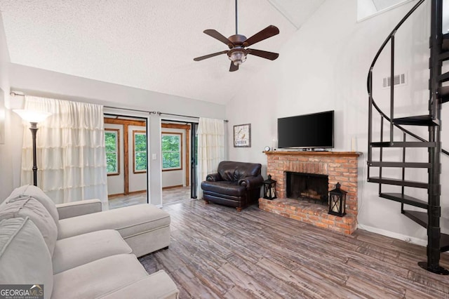 140 Indian Ridge Ct, Waleska, GA 30183 - living room with high vaulted ceiling, a ceiling fan, wood finished floors, a brick fireplace, and a textured ceiling