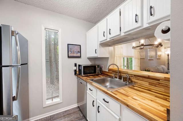 140 Indian Ridge Ct, Waleska, GA 30183 - kitchen with stainless steel appliances, dark wood-style flooring, white cabinetry, a textured ceiling, and a chandelier