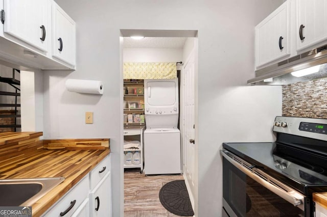 140 Indian Ridge Ct, Waleska, GA 30183 - kitchen featuring stainless steel electric stove, stacked washing machine and dryer, under cabinet range hood, white cabinetry, and light wood finished floors
