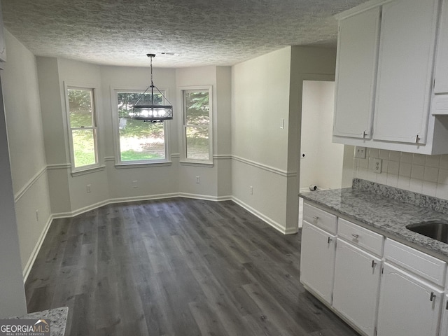 56 Ridgewood Ct, Mcdonough, GA 30252 - unfurnished dining area with healthy amount of natural light, a textured ceiling, dark wood-type flooring, and a chandelier