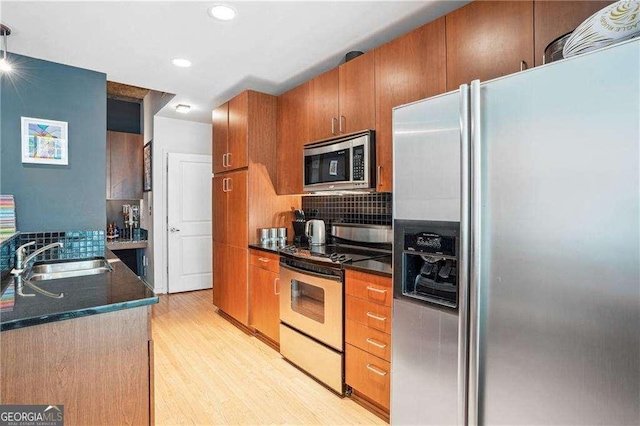 943 Peachtree St NE Unit 902, Atlanta, GA 30309 - kitchen with stainless steel appliances, dark countertops, light wood-style flooring, backsplash, and brown cabinets