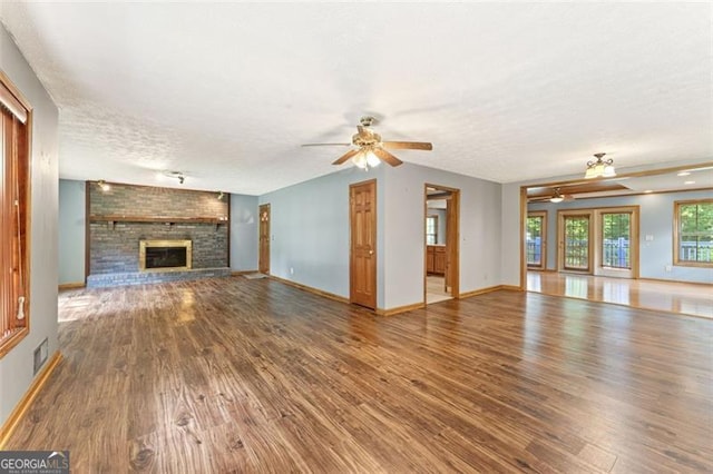 137 Trickum Hills Dr, Woodstock, GA 30188 - unfurnished living room featuring ceiling fan, wood finished floors, a textured ceiling, and a brick fireplace