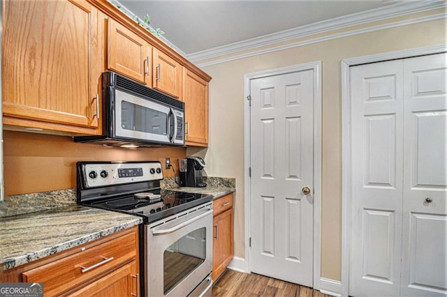 2437 Charleston Pointe Ct SE, Atlanta, GA 30316 - kitchen featuring appliances with stainless steel finishes, ornamental molding, light wood-style flooring, light stone countertops, and brown cabinets