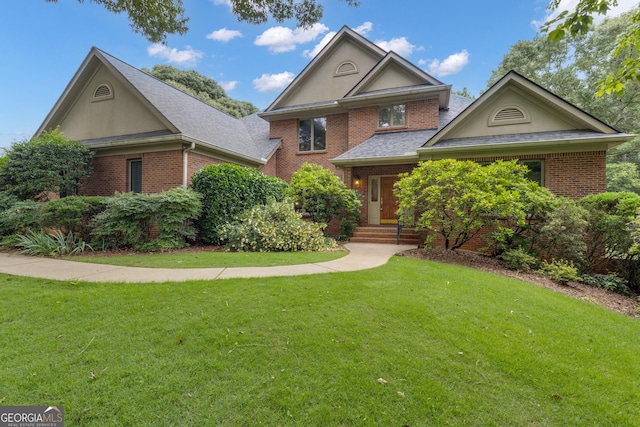 821 Carnellian Ln, Peachtree City, GA 30269 - view of front of house with brick siding, a front yard, stucco siding, and roof with shingles