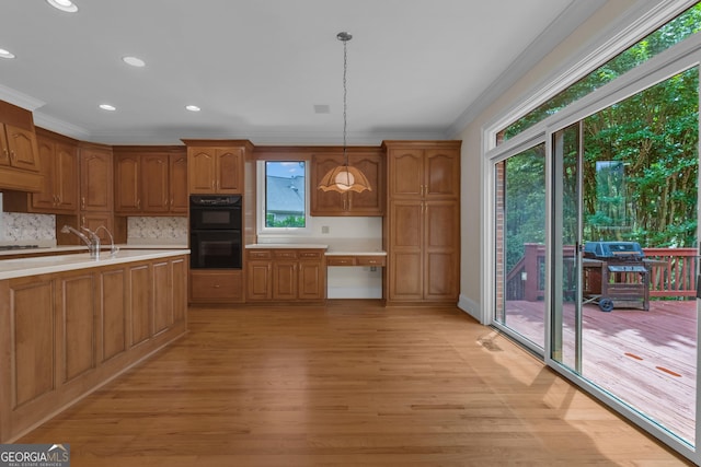 821 Carnellian Ln, Peachtree City, GA 30269 - kitchen featuring crown molding, healthy amount of natural light, light countertops, light wood-style floors, and decorative backsplash