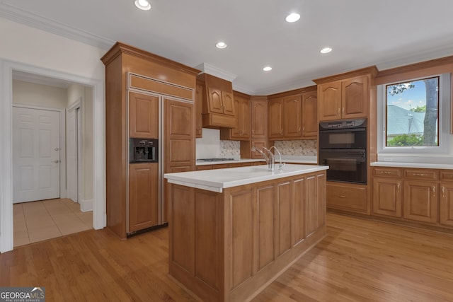 821 Carnellian Ln, Peachtree City, GA 30269 - kitchen featuring paneled built in fridge, light wood-type flooring, light countertops, decorative backsplash, and an island with sink