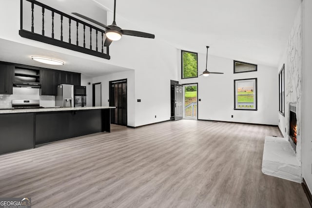 50 Hearthstone Dr, Newnan, GA 30263 - unfurnished living room featuring ceiling fan, high vaulted ceiling, a fireplace, and light wood-style flooring