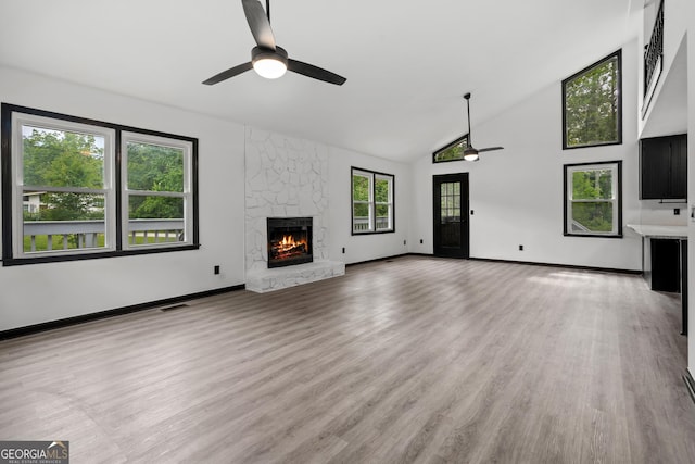 50 Hearthstone Dr, Newnan, GA 30263 - unfurnished living room featuring ceiling fan, a stone fireplace, high vaulted ceiling, and light wood-style flooring