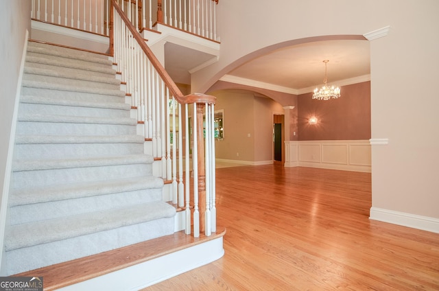 128 Laurel Ridge Dr, Alpharetta, GA 30004 - staircase with arched walkways, crown molding, wood finished floors, and a chandelier