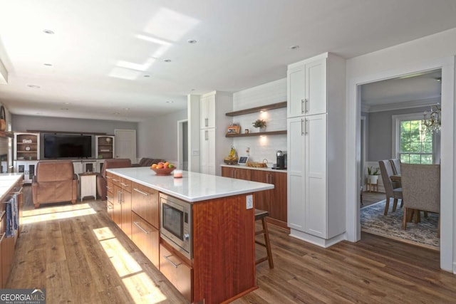 1908 Musket Ct, Stone Mountain, GA 30087 - kitchen featuring stainless steel microwave, wood finished floors, a kitchen island, a kitchen breakfast bar, and light countertops