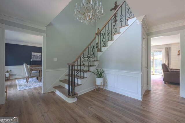 1908 Musket Ct, Stone Mountain, GA 30087 - stairs with wood finished floors, ornamental molding, a chandelier, a decorative wall, and wainscoting