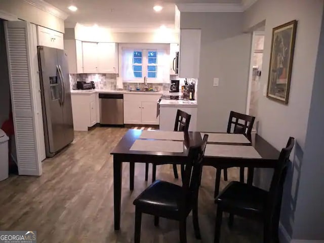 121 N Church St Unit 101, Clayton, GA 30525 - kitchen with appliances with stainless steel finishes, crown molding, white cabinetry, backsplash, and light countertops