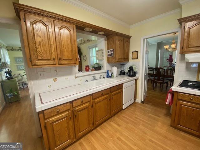 1812 Morgan Cantey Dr, Lanett, AL 36863 - kitchen featuring white dishwasher, tile counters, crown molding, light wood-style floors, and backsplash