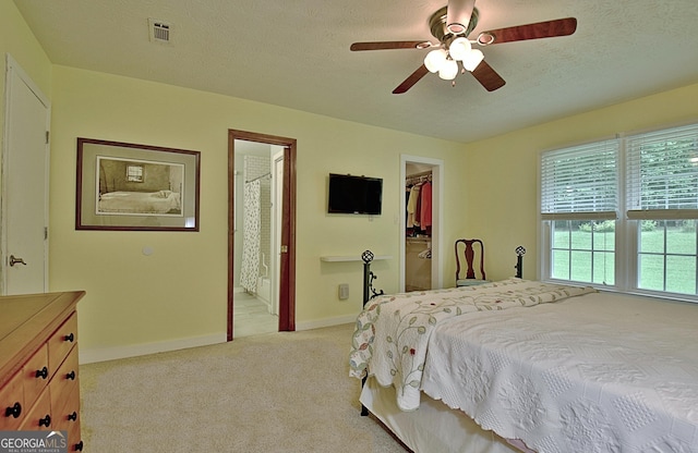 210 Grandchester Way, Fayetteville, GA 30215 - bedroom with light colored carpet, a walk in closet, a textured ceiling, connected bathroom, and ceiling fan