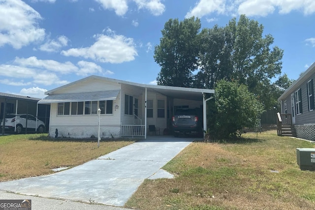 435 Village Cir SW, Winter Haven, FL 33880 - manufactured / mobile home with concrete driveway, a front yard, and a carport