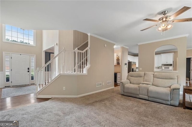 2772 Hillgrove Dr, Dacula, GA 30019 - living area featuring stairs, carpet, a ceiling fan, ornamental molding, and arched walkways